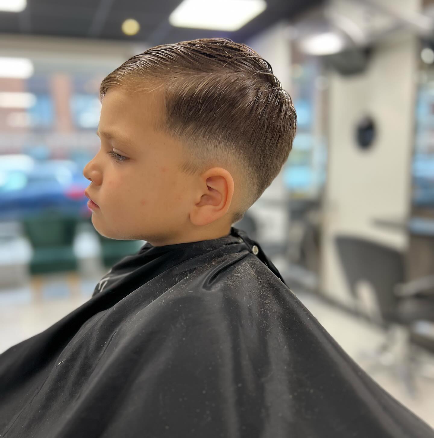 Jongen in profiel met een fade en een zijscheiding, in de salon